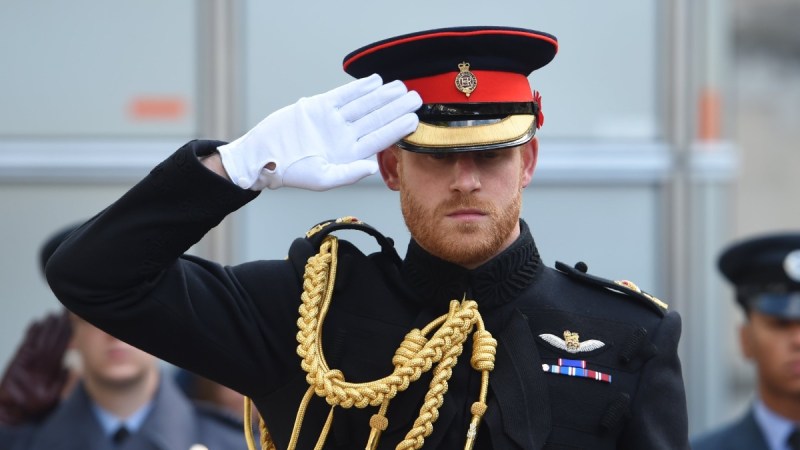 Prince Harry wears his military uniform and salutes something off camera