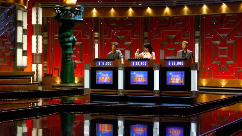 Celebrity contestants on Jeopardy! stand behind their podiums on set