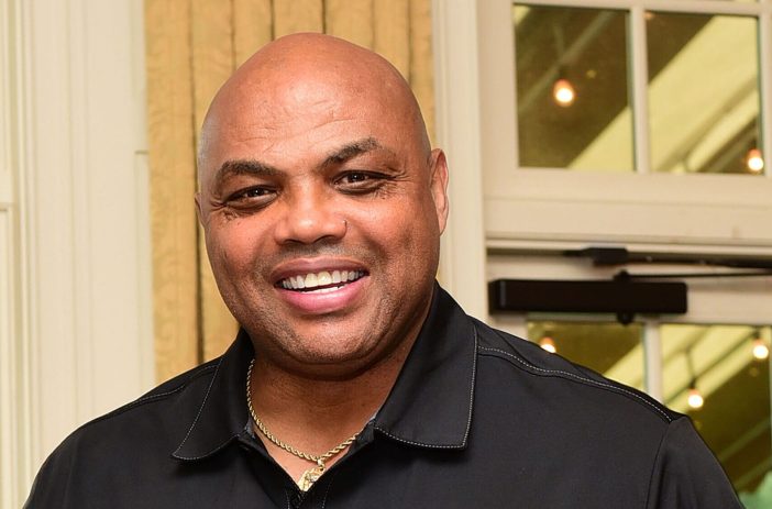 Charles Barkley smiling and wearing a black polo shirt
