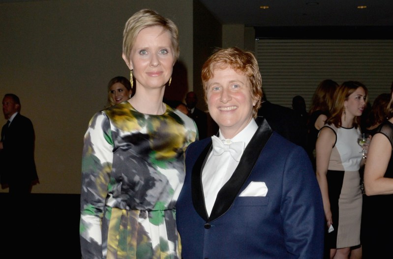 Cynthia Nixon and wife Christine Marinoni. Cynthia is wearing a green and white dress; Christine is wearing a blue suit.