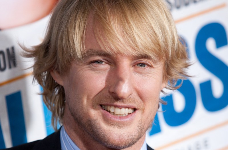 A close up shot of Owen Wilson's face; he's smiling and wearing a blue shirt.