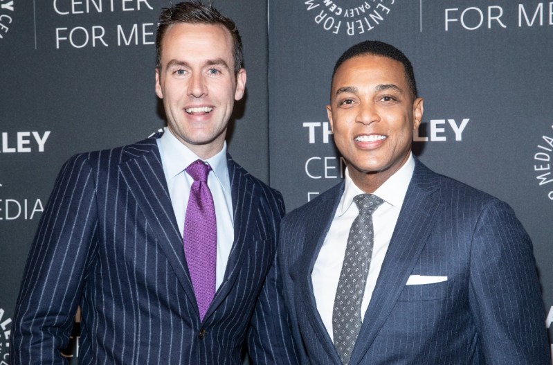 Don Lemon and his partner, Tim Malone, smiling at an event and wearing navy blue pin striped suits.
