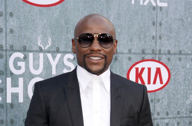 Floyd Mayweather wearing a black suit with a white shirt and tie.