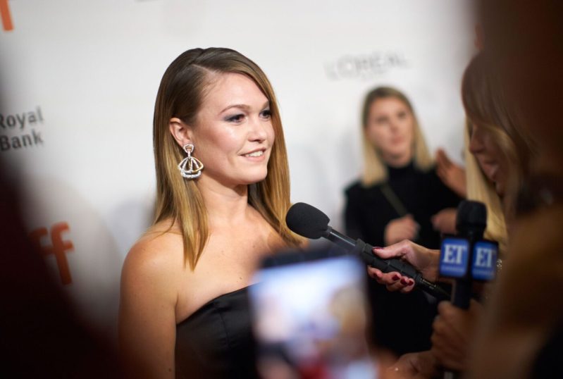 Actress Julia Stiles speaks to reporters in a black strapless dress