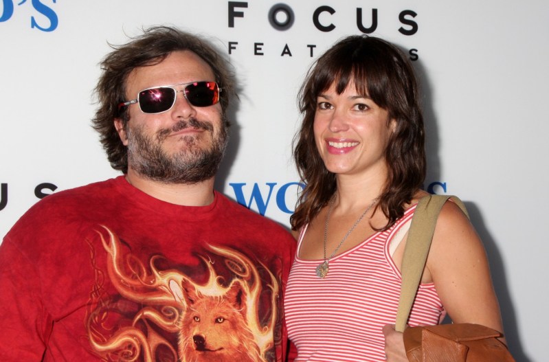 Jack Black wearing a red shirt with flames and a wolf on the front He's with his wife, Tanya Haden, who is wearing a red and white shirt.