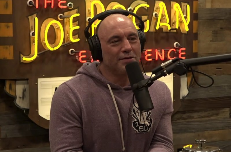 Joe Rogan in a hoodie with headphones while doing his podcast.