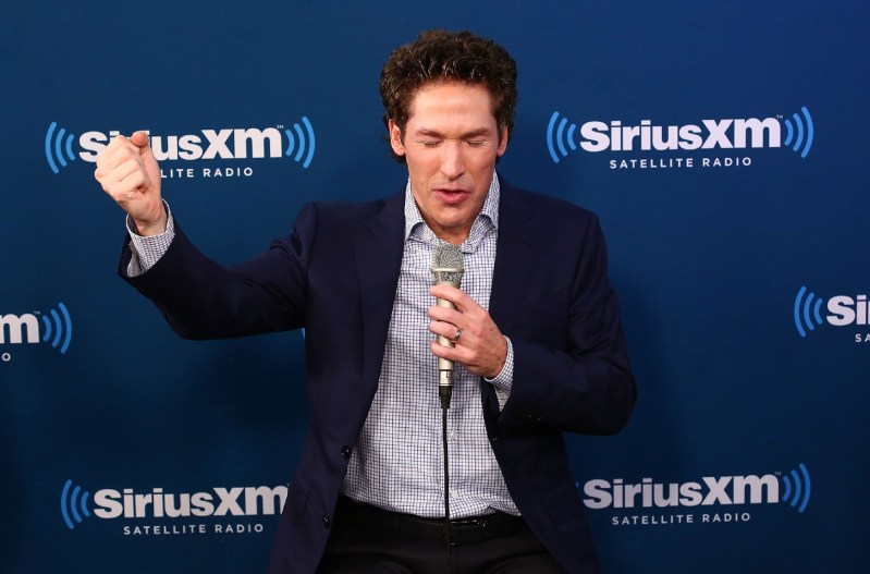 Joel Osteen in a blue suit with his fist in the air.