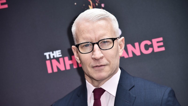 Anderson Cooper wears a navy suit and pink shirt on the red carpet