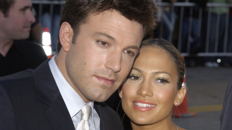 Ben Affleck, in a dark tux, cozies up to Jennifer Lopez, in a colorful dress, on the red carpet