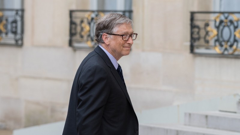 Bill Gates walks into a French palace while wearing a dark suit