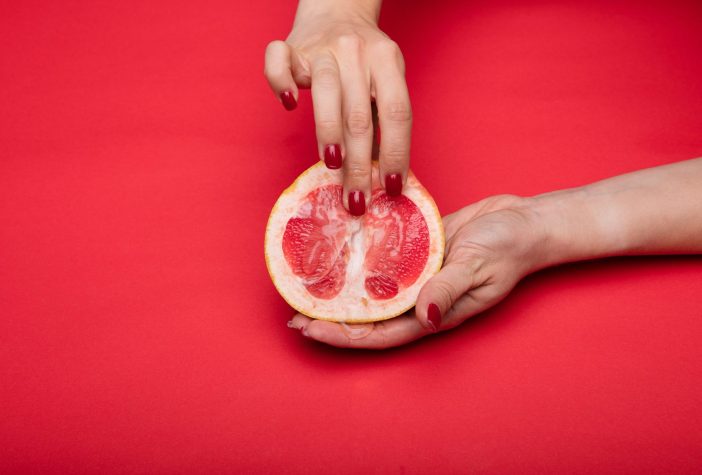 Cut grapefruit with a woman's hand in a sexually suggestive position/