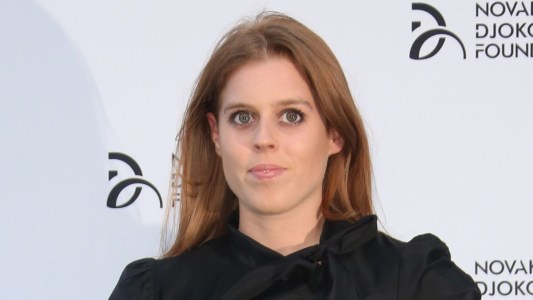 Princess Beatrice wears a black dress against a white background