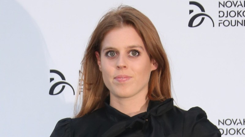 Princess Beatrice wears a black dress against a white background