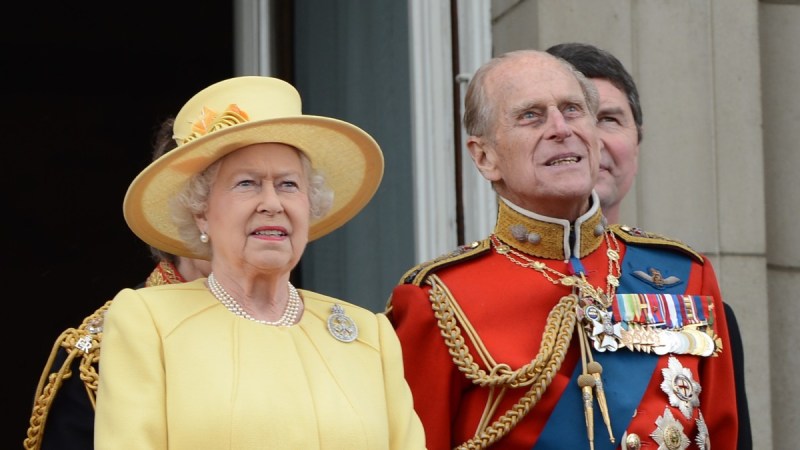 Queen Elizabeth wears a yellow dress as she stands next to Prince Philip, in his military outfit