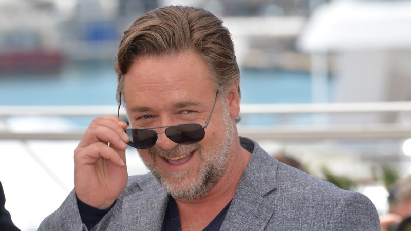 Russell Crowe cheekily lowers his sunglasses while at a film festival