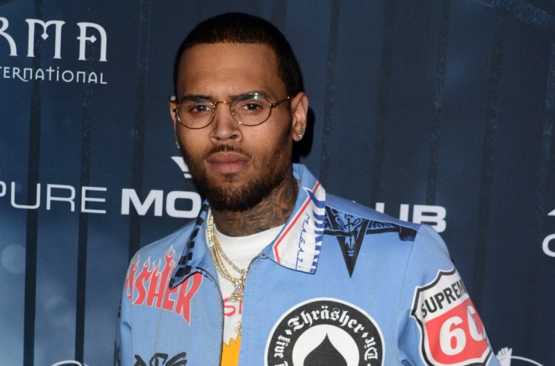 Chris Brown in a blue racing jacket with various logos printed on it.