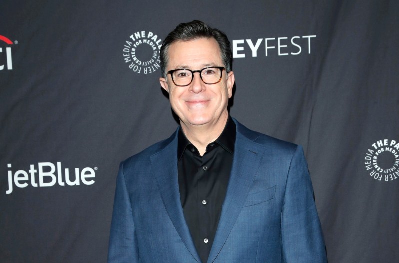 Stephen Colbert smiling and wearing a blue suit.