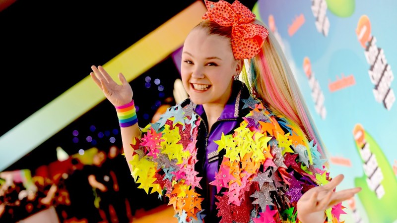 Jojo Siwa wears a colorful star jacket on the red carpet while wearing her usual large hair bow