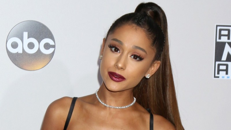 Ariana Grande wears a lacy black top and white pants on the red carpet