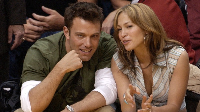 Ben Affleck and Jennifer Lopez lean in close to each other during a basketball game