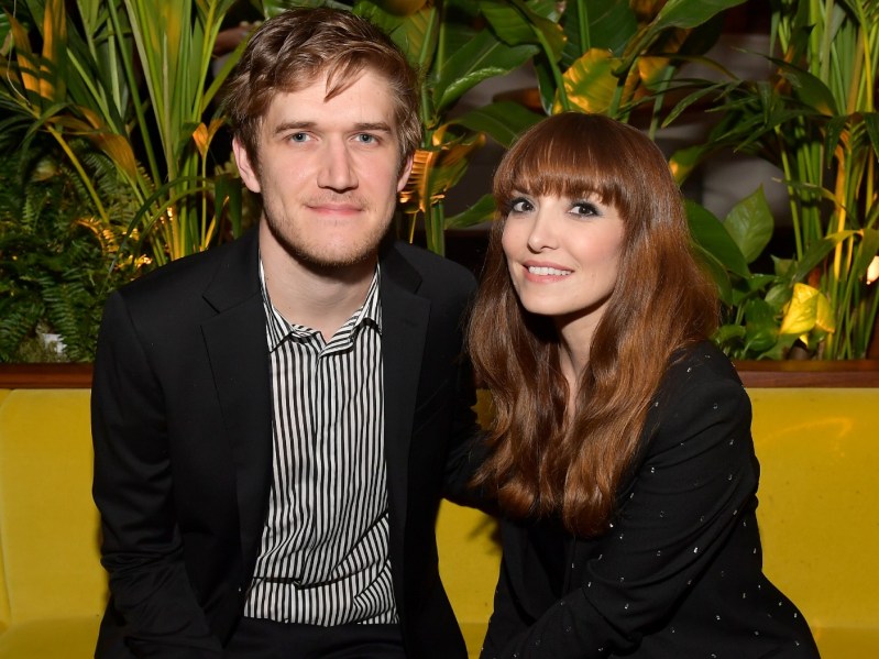 Bo Burnham (L) and Lorene Scafaria sitting on yellow couch with plants in the background