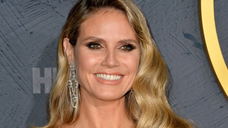 Heidi Klum wears a dress with a plunging neckline against a gray background