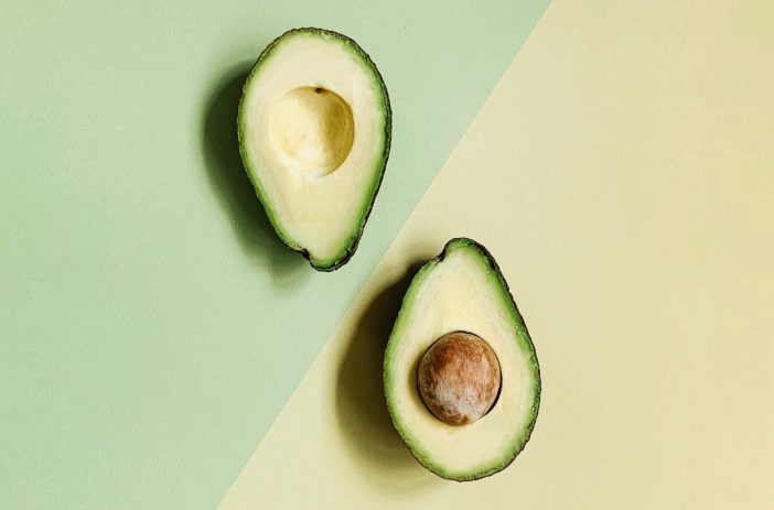 Image of a sliced avocado against a green and yellow background.