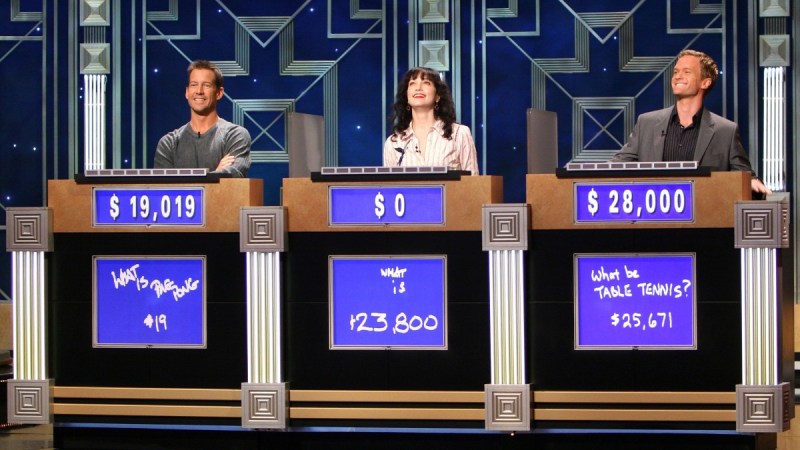Three celebrity contestants compete on the set of Jeopardy! behind the iconic podiums