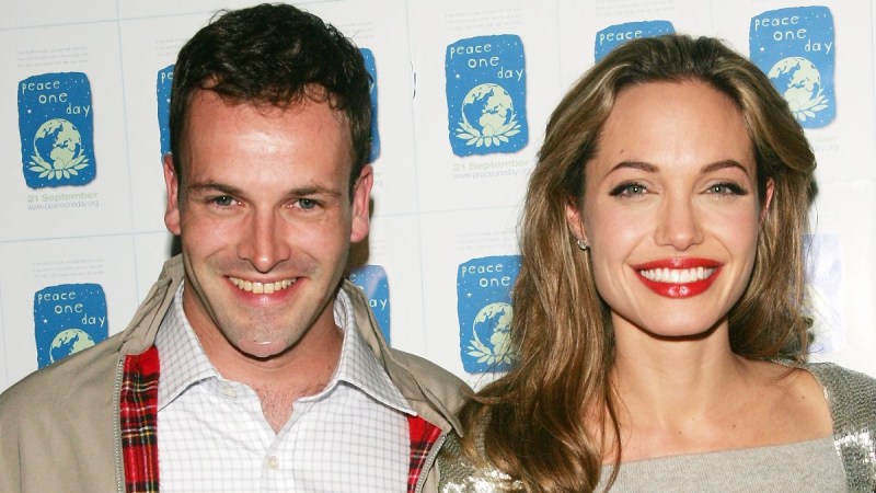 Jonny Lee Miller and Angelina Jolie stand close together at the premiere of a film