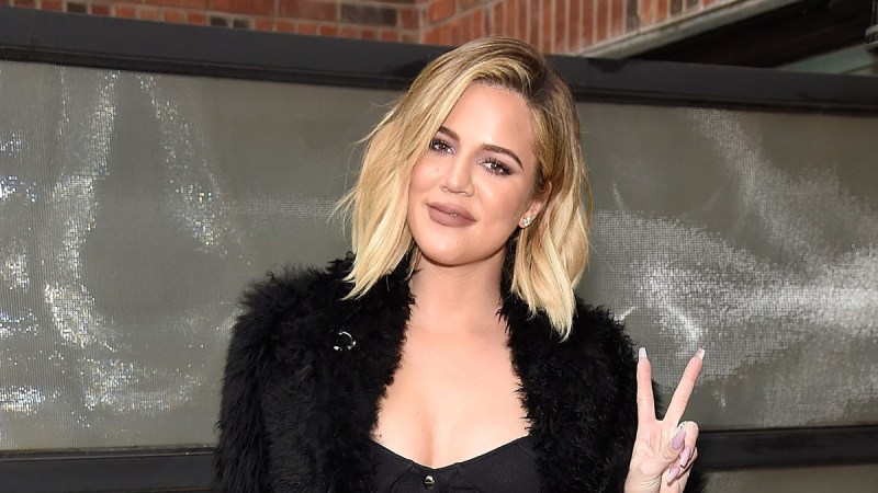 Khloe Kardashian flashes a peace sign at photographers while wearing all black