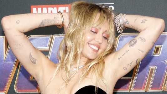 Miley Cyrus strikes a seductive pose while wearing a black dress on the red carpet
