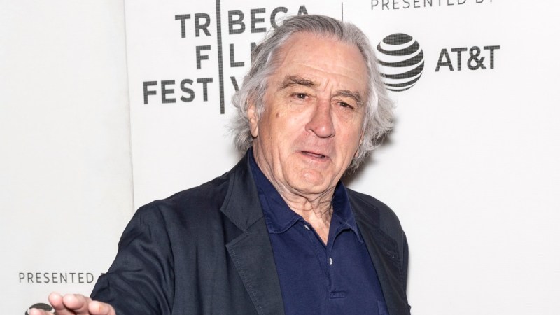 Robert De Niro wears a dark suit jacket against a white background