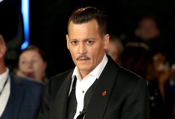 Johnny Depp in a black tux with undone bowtie and slicked back hair at a film premiere.
