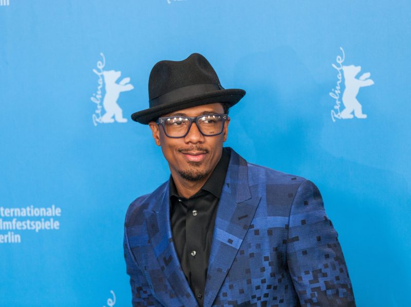 Nick Cannon in a patterned navy suit and black fedora on the red carpet.
