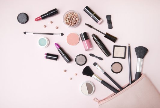 Stock photo of a makeup bag with cosmetics spilling out.