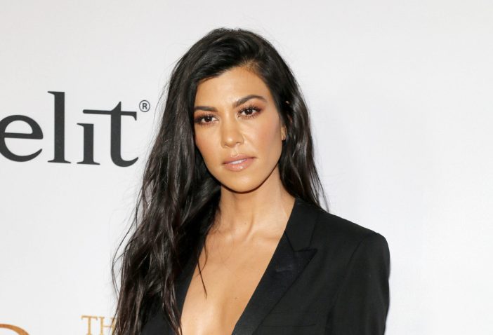 Kourtney Kardashian wearing a low cut black suit jacket on the red carpet.