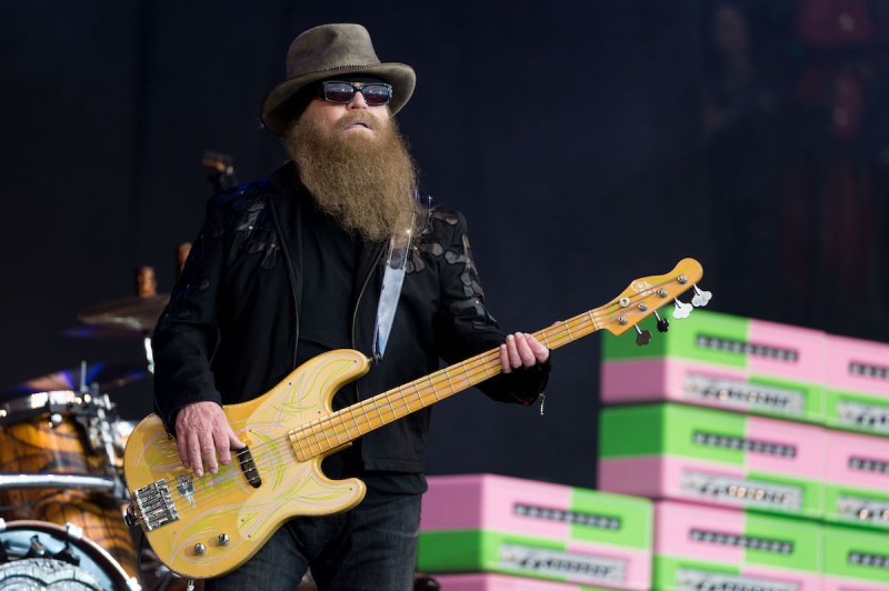 Dusty Hill playing bass on stage in a black outfit
