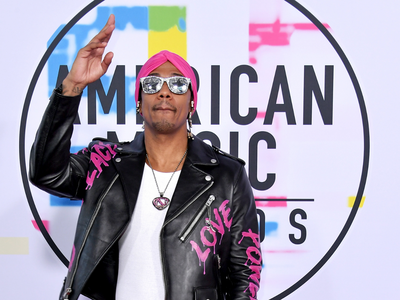 Nick Canon wears a black leather jacket with the words "love" and "power" in hot pink on the sleeves.