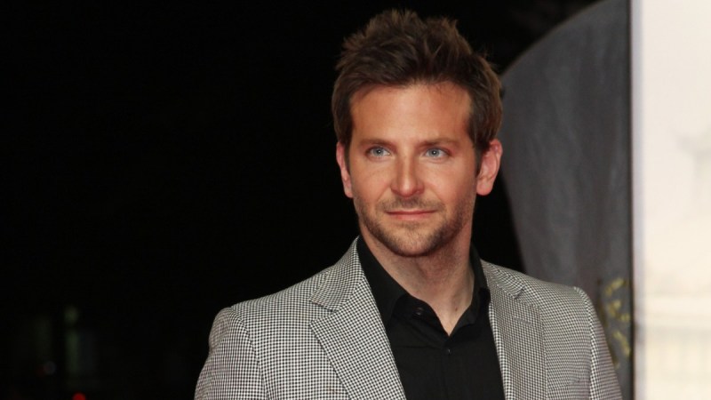 Bradley Cooper wears a gray suit and black shirt on the red carpet