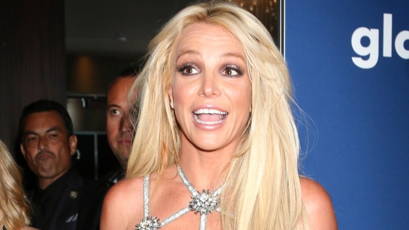 Britney Spears smile animatedly while wearing a silver dress on the red carpet