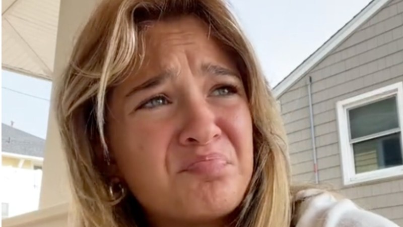 Claudia Conway wears a white hoodie as she films a video outdoors