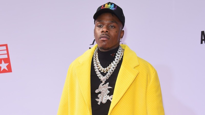 DaBaby wears a large yellow coat over a black shirt on the red carpet