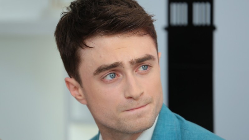 Daniel Radcliffe looks off to the side while wearing a blue suit that matches his dreamy eyes