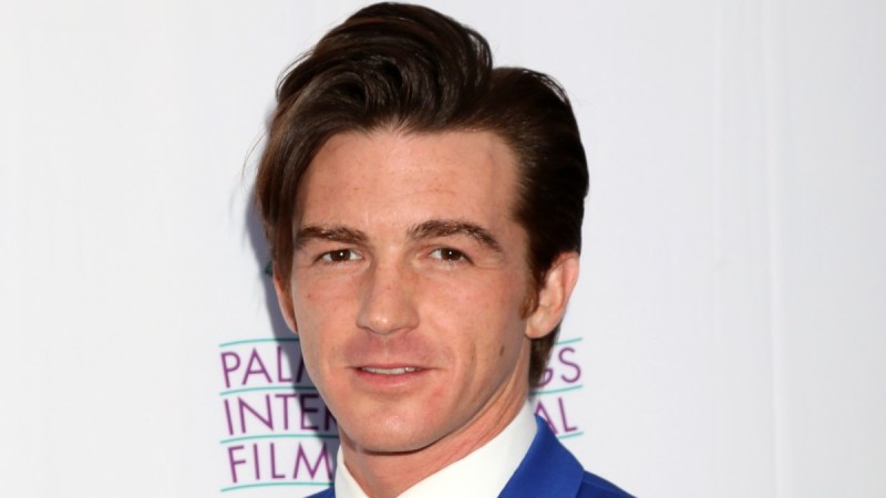 Drake Bell wears a blue suit against a blue background