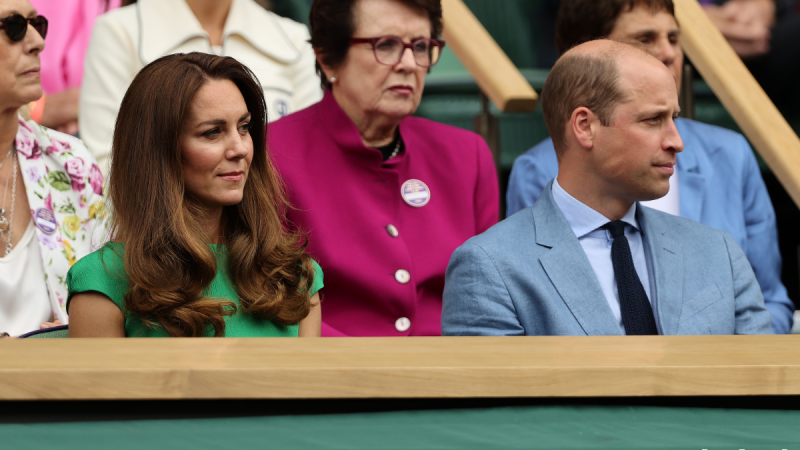 Kate Middleton, in a green dress, sits with Prince William, in blue suit, in the stands at Wimbledon