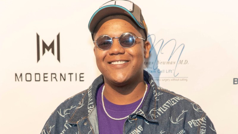 Kyle Masse wears a gray jacket, hat and sunglasses on the red carpet