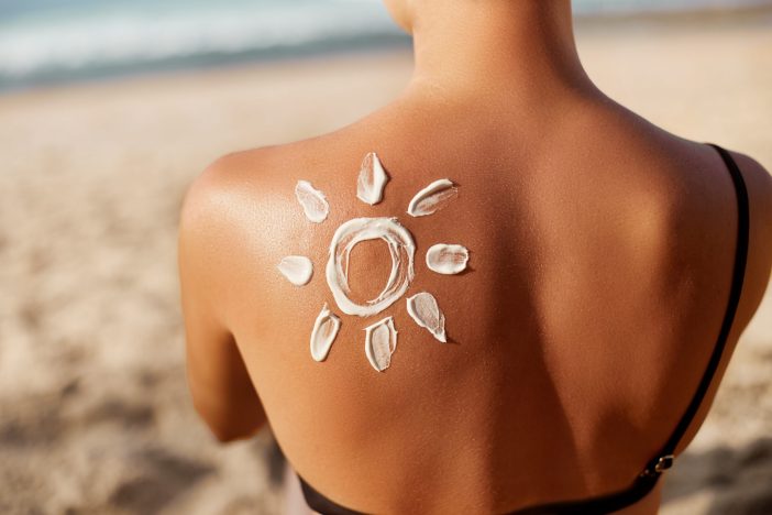 Image of tan woman with a sunscreen drawn sun on her back.