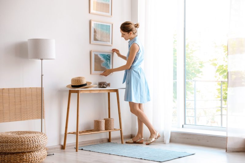 Image of woman decorating her home in a dress.