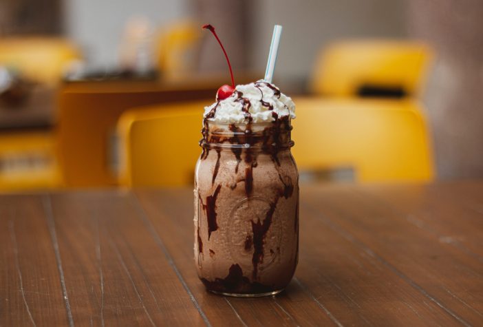 Milkshake with chocolate syrup, whipped cream, and a cherry.