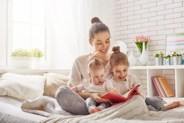 Image of a young mom reading to her kids